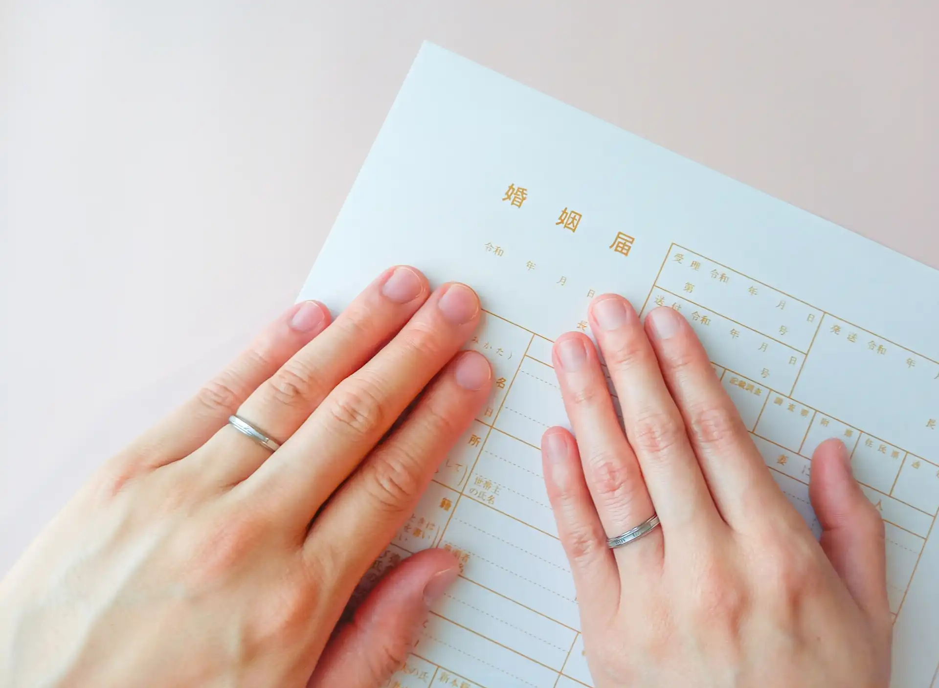婚姻届に置かれた指輪をつけた二人の手